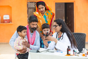 Young Indian Female Doctor with rural family give medicine outdoor village hospital,Healthcare...