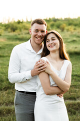 happy guy hugs his bride at sunset of the day. portrait of a couple in love. happy young people of european appearance. summer honeymoon day