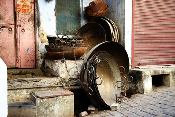 Closeup shot of worn copper pots on the ground near a partly destroyed building in Udaipur, India