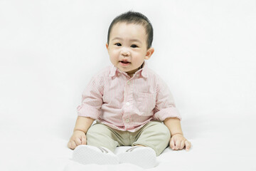 Stylish fashionable kid. Toddler baby boy model in casual clothes.Happy smiling Adorable asian 
child in pink shirt sitting on white bedsheet.Fashion and Style. 