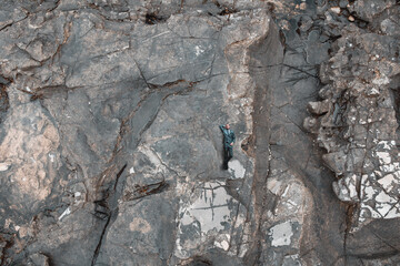 Businessman laying on stone texture. Aerial view to man on rock