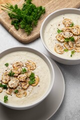 Bowl with mushroom cream soup and parsley on grey table. Champignon soup.