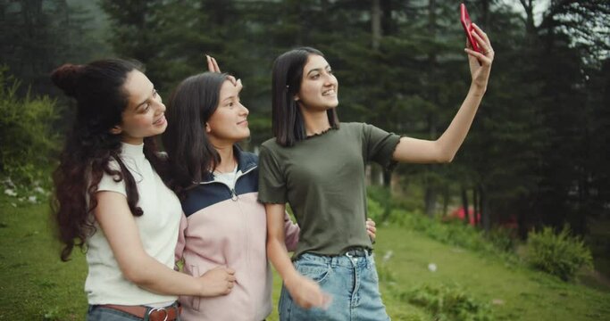 A slow-motion of three attractive young women from India taking fun selfies in the woods