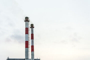 Two industrial pipes of white and red color against the sky