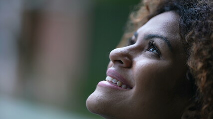 Spiritual black woman closing eyes in contemplation, Brazilian girl opening eye to sky with HOPE