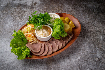 Serving a dish from the restaurant menu. Sliced beef tongue with pickles, cabbage, sauces and herbs...
