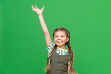 a little girl stretched her hand up against a green isolated background.