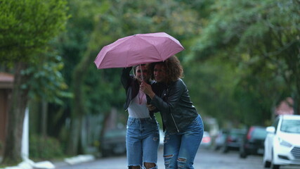 Friends sharing umbrella together during rainy day