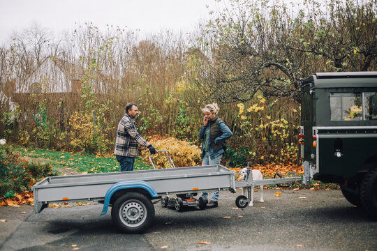 Female and male friends talking while standing by sports utility vehicle