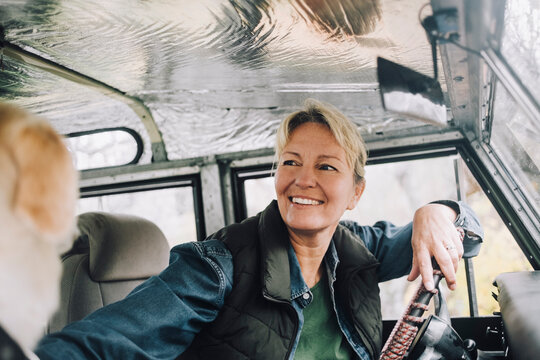 Smiling woman looking away while sitting in sports utility vehicle