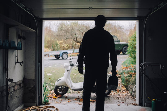 Rear view of man standing in garage