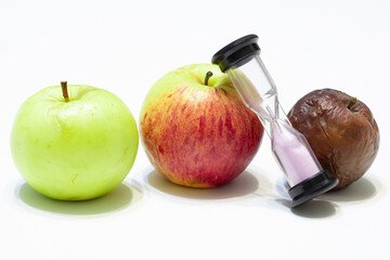 Green, red and rotten apple and time, hourglass on a white background. Young and old, concept