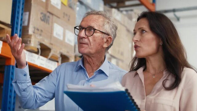 Mature woman and man analyzing documents in the warehouse. Shot with RED helium camera in 8K.  