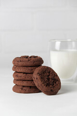 Brownie chocolate biscuits, homemade cakes. Milk in a glass on a light background.
Close-up, copy space, white background.