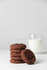 Brownie chocolate biscuits, homemade cakes. Milk in a glass on a light background. Copy space, white background.