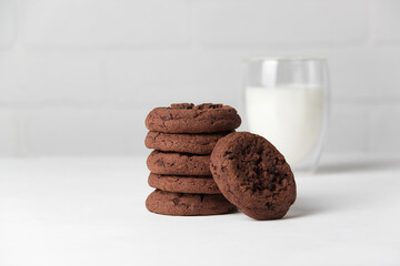 Brownie chocolate biscuits, homemade cakes. Milk in a glass on a light background.
Close-up, copy space, white background.