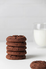 Brownie chocolate biscuits, homemade cakes. Milk in a glass on a light background. Close-up, copy space, white background.