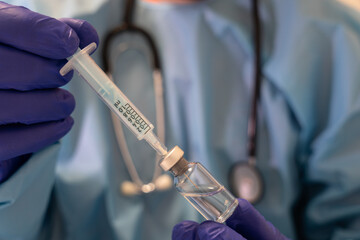 photo of a doctor with blue gloves preparing the covid-19 vaccine