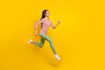 Fototapeta na wymiar Photo of sweet charming mature lady dressed striped shirt running fast jumping high empty space smiling isolated yellow color background