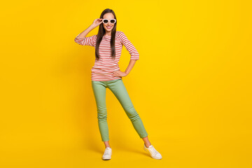 Fototapeta na wymiar Photo of charming pretty young woman wear striped shirt arm dark glasses smiling walking isolated yellow color background