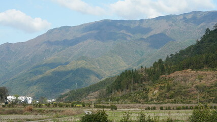 Naklejka premium The beautiful mountains view with the green forest and flowers field in the countryside of the southern China 