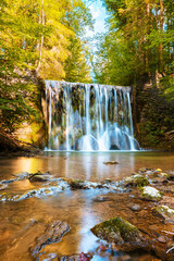 Vertical shot of a beautiful flowing cascading waterfall in a forest