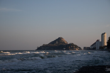 sea waves on the bay with mountain and buildings at the back