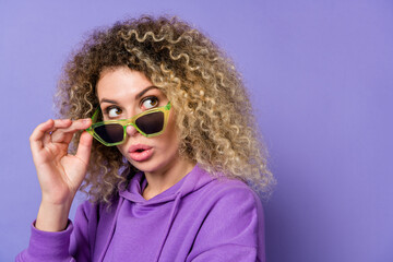 Photo of adorable impressed lady dressed hoodie arm dark spectacles empty space isolated purple color background