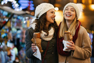 Happy women friends enjoying christmas market and having fun together outdoors. - obrazy, fototapety, plakaty