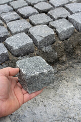 worker shows how a setts are worked to regular shape, distinct from a cobblestone
