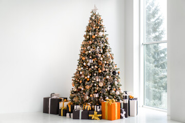 Christmas tree in white interior with stylish black and orange gift box