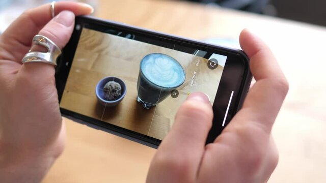 Woman hands take pictures of coffee using a smartphone. Matcha coffee and dried fruit sweets.