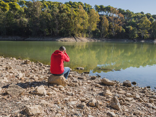 Young man with hands on head near lake. Loneliness and depression concept. Mental problems