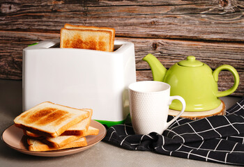 Toaster with bread slices and cup of coffee on table