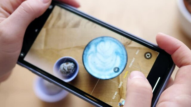 Woman hands take pictures of coffee using a smartphone. Matcha coffee and dried fruit sweets.