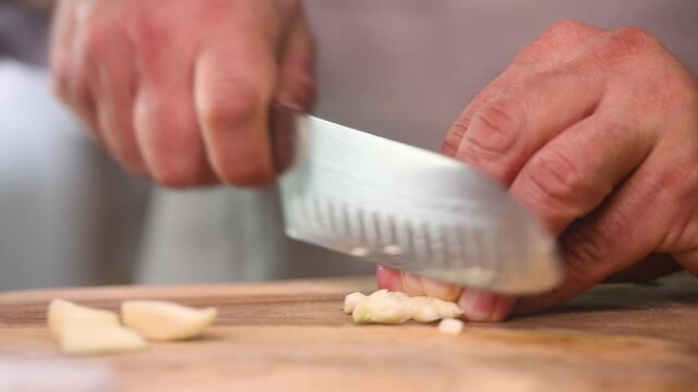 Chef cuting garlic with knife on a table