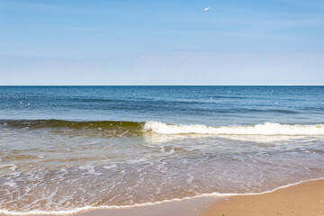 Fototapeta na wymiar sea waves against the background of yellow sand and blue sky