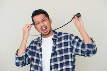 Adult Asian man screaming crazy while plug in a power cable to his head