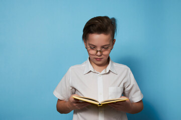 Portrait school boy with a book over blue background