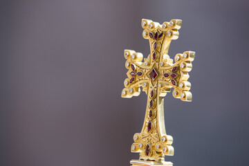 Closeup shot of a gold Armenian cross on a gray background