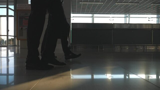 Feet of two businessmen walking at terminal of airport. Legs of business men stepping together. Colleagues going indoors. Slow motion Low angle of view Close up