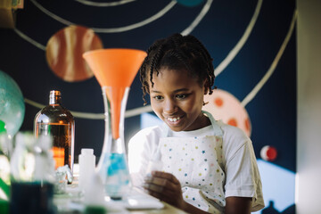 Smiling female student learning science project at home