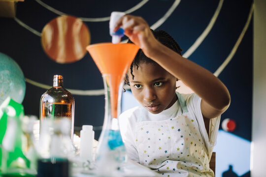 Ambitious girl mixing chemical solution while learning science project at table