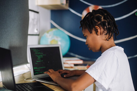 Female student learning coding on laptop at table