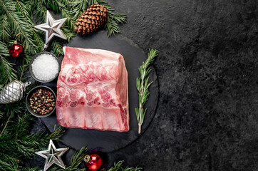 Christmas raw pork steaks, with fir tree and new year decorations on stone background with copy space for your text