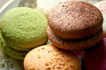 Variety of flavors of macaroon pastries in a white plate on a wooden background. Close up, selective focus
