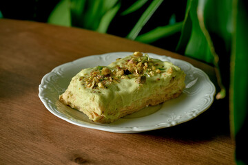 Pistachio cake in white plate on wood background