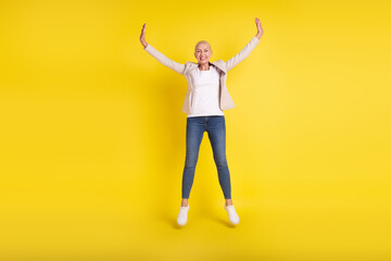 Full body photo of cheerful aged woman good mood jump up feel-young isolated over yellow color...