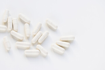 White capsule pills on white background, supplement and medicine concept. Closeup, copy space