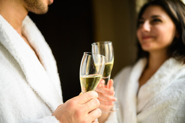 Cheerful couple in bathrobe toasting champagne glasses - obrazy, fototapety, plakaty